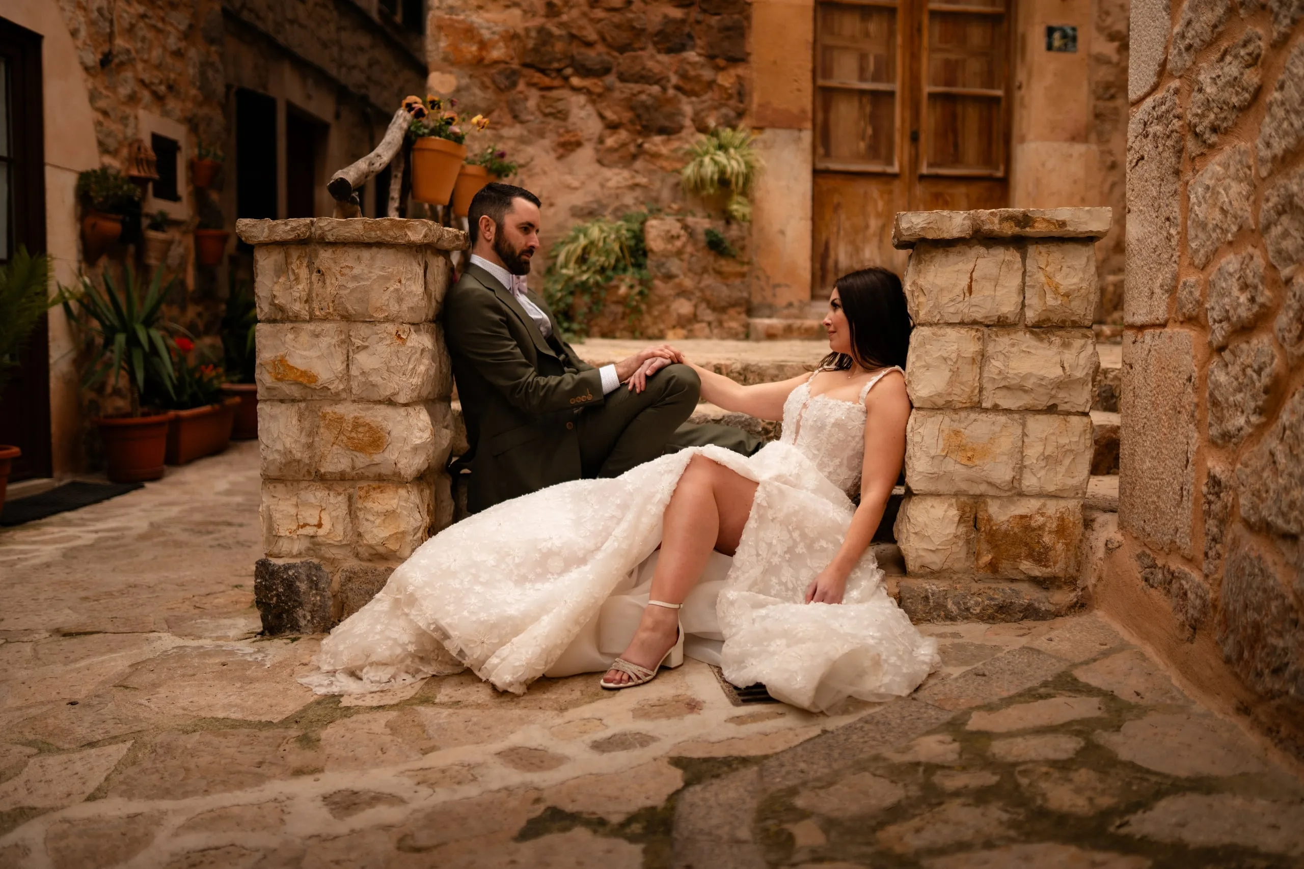 Elopement-Paar ruht in einer Gasse aus Naturstein, das Brautkleid ausgebreitet