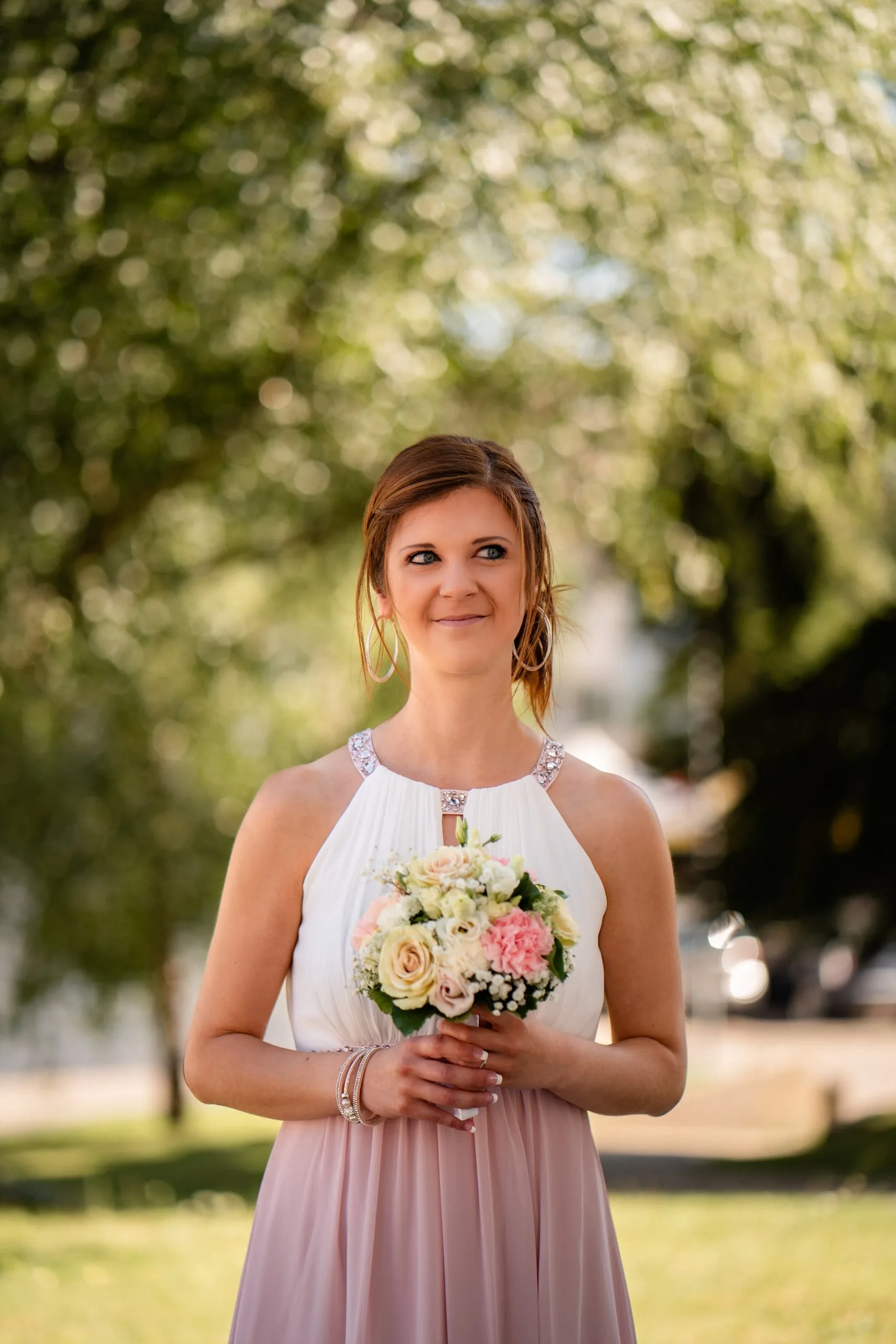 Braut im zweifarbigen Kleid hält ihren Strauss und lächelt verschmitzt zur Seite