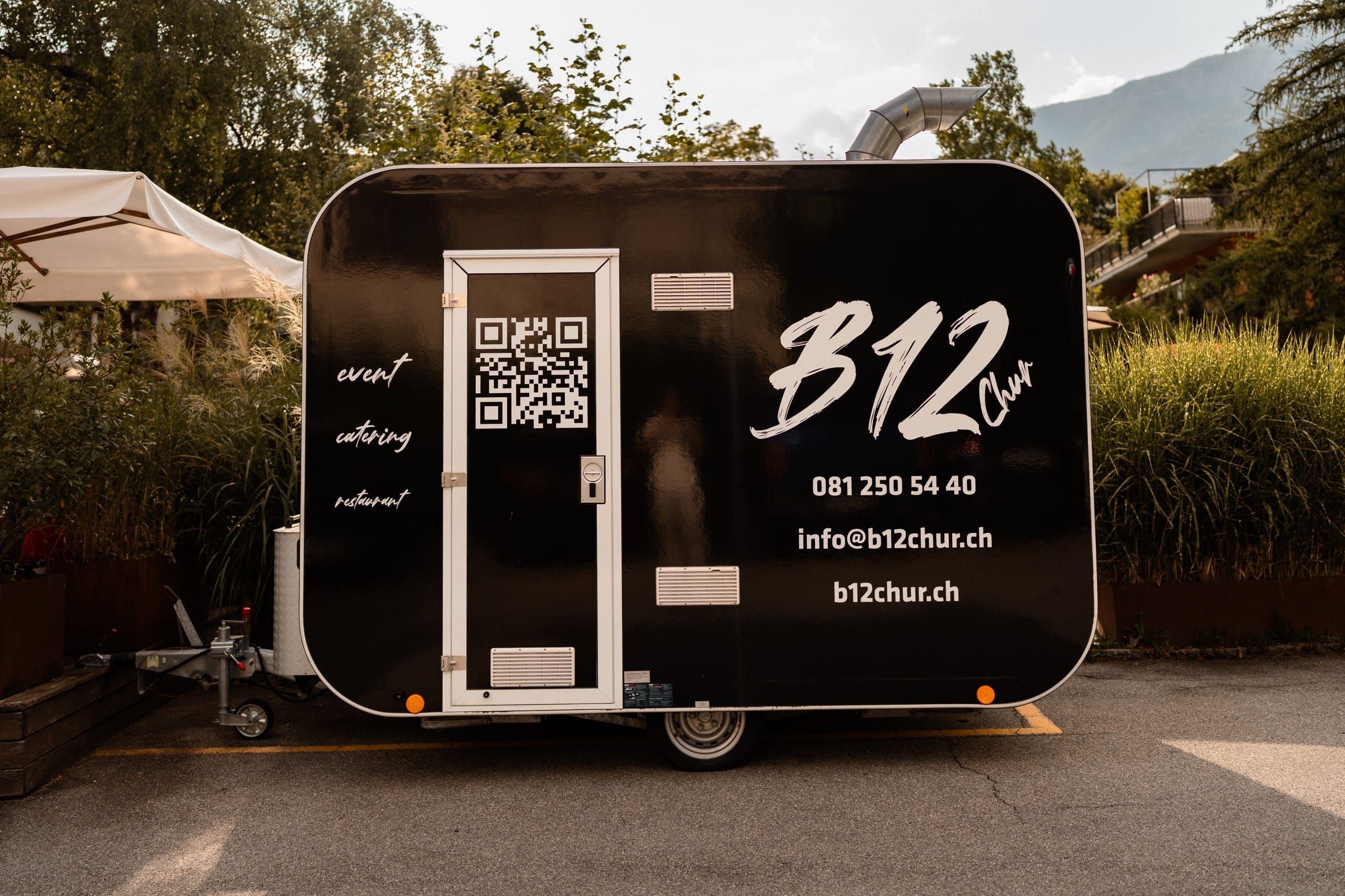 Der schwarze Catering-Trailer des B12 Chur mit Logo und Kontaktangaben