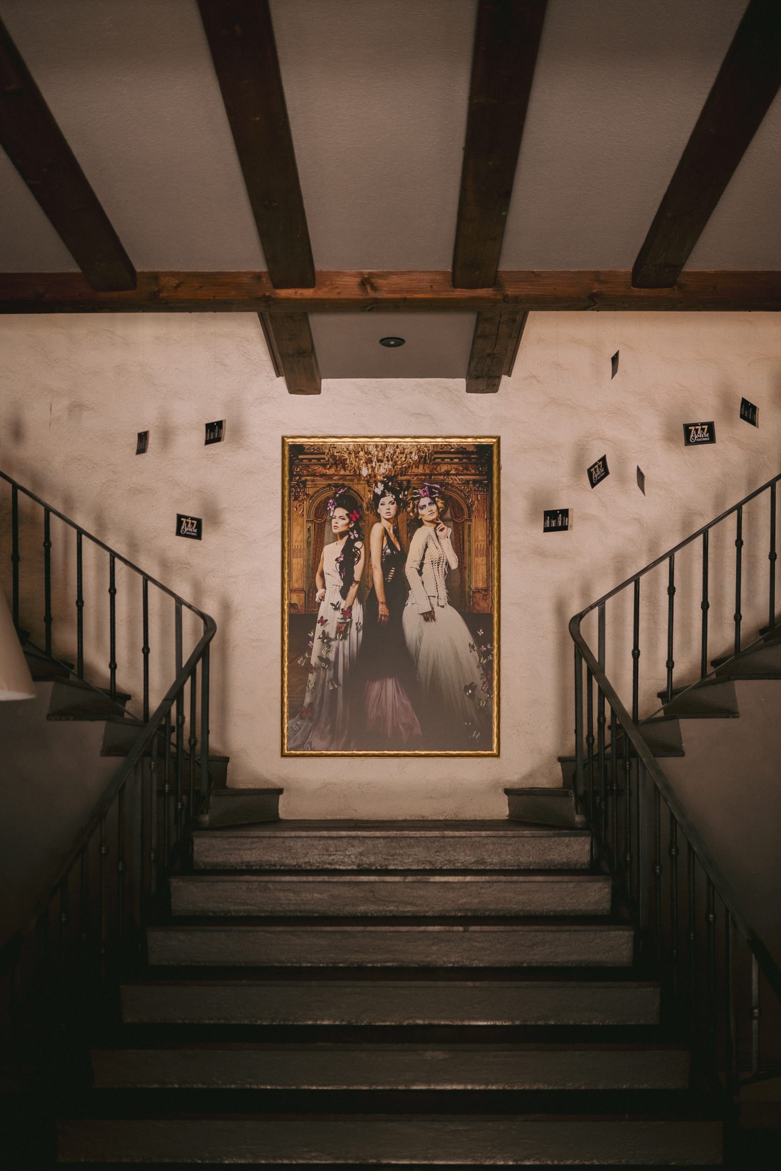 Stimmungsvolles Treppenhaus im Schloss Maienfeld mit Holzbalkendecke und gerahmter Kunst