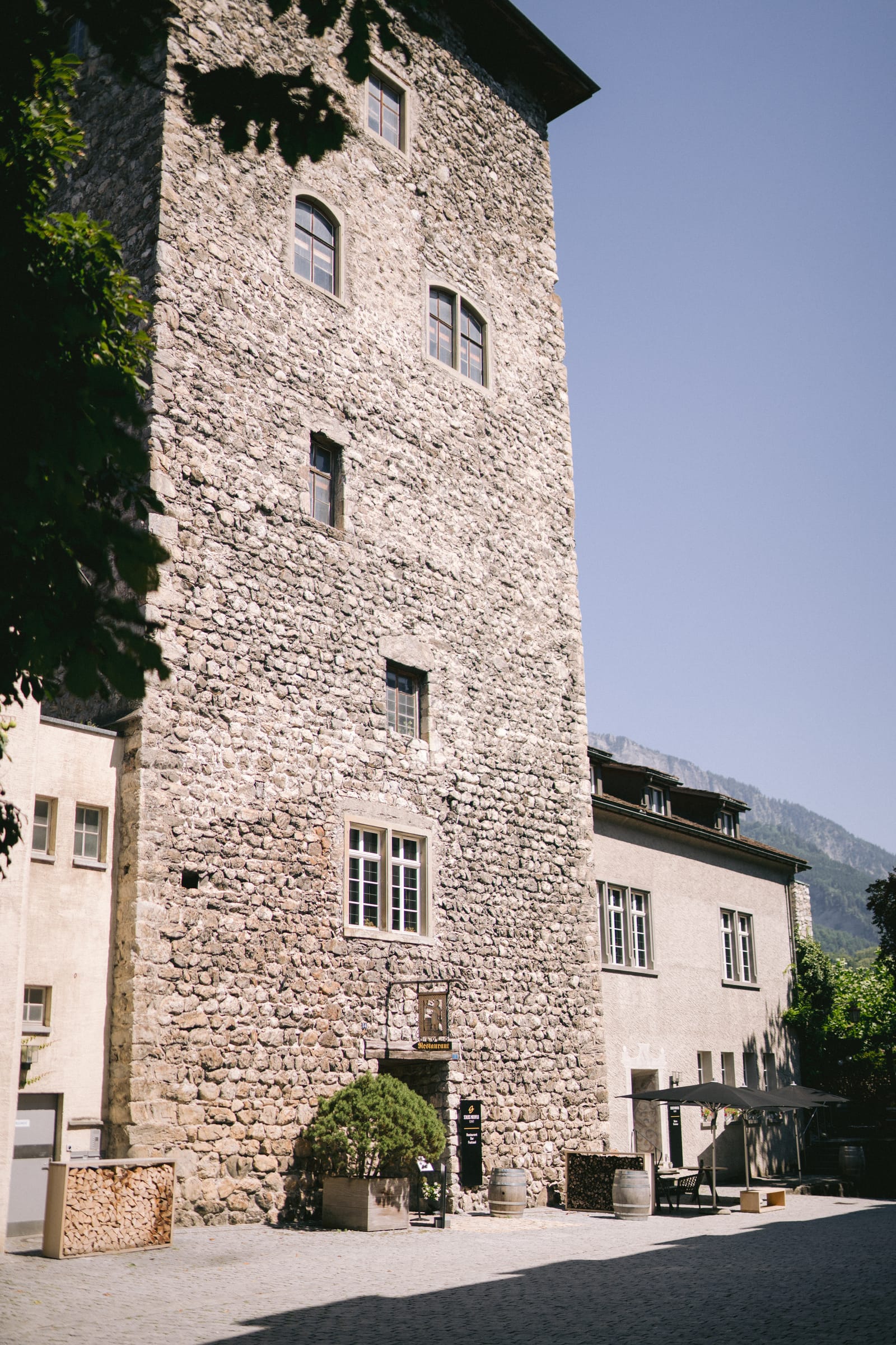 Der historische Steinturm von Schloss Maienfeld über dem Innenhof, dahinter die Berge der Bündner Herrschaft