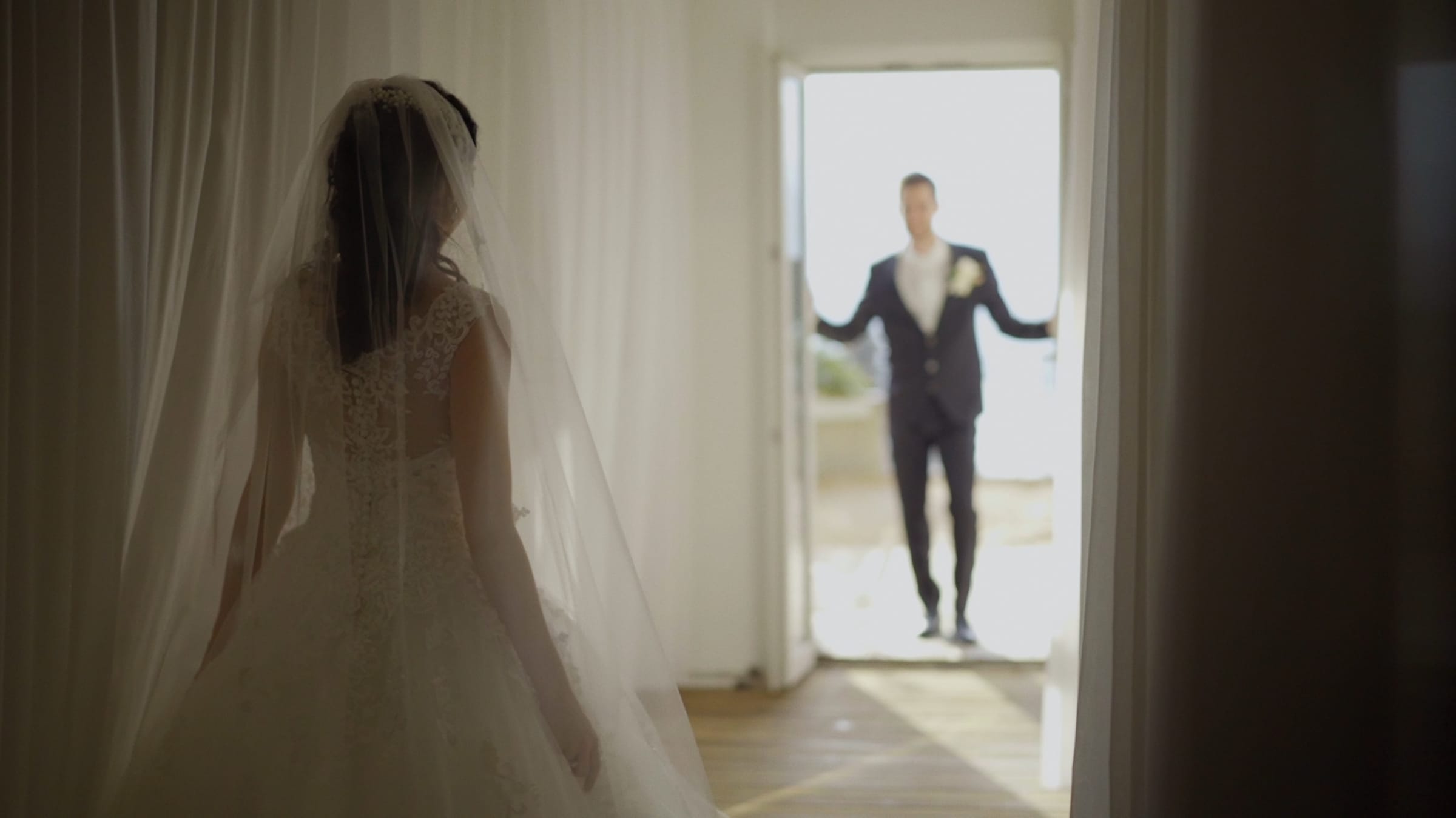 Braut mit Schleier geht dem Bräutigam im hellen Gegenlicht entgegen – emotionaler Moment am Hochzeitstag
