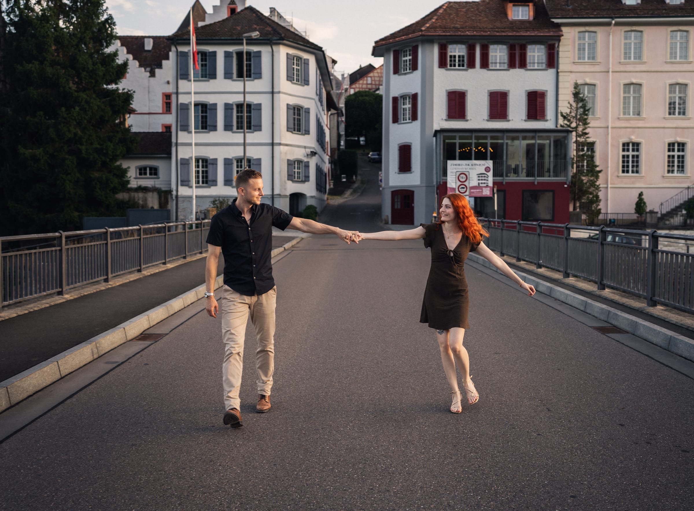 Yanick und Tatjana halten sich an einer Hand auf der Brücke in Kaiserstuhl, Altstadthäuser im Hintergrund