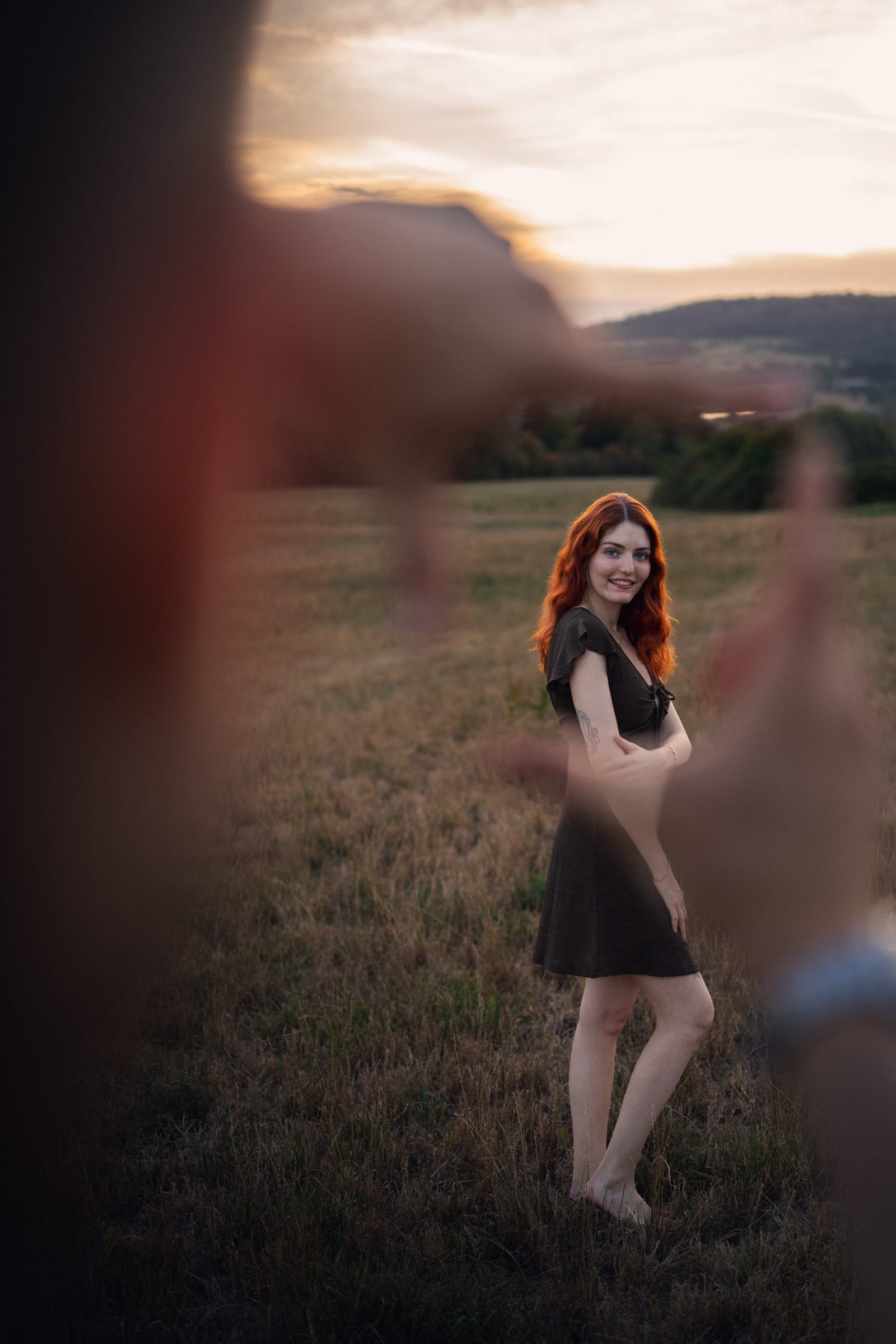Tatjana tanzt auf der Weide im Sonnenuntergang, Yanicks Hand unscharf im Vordergrund