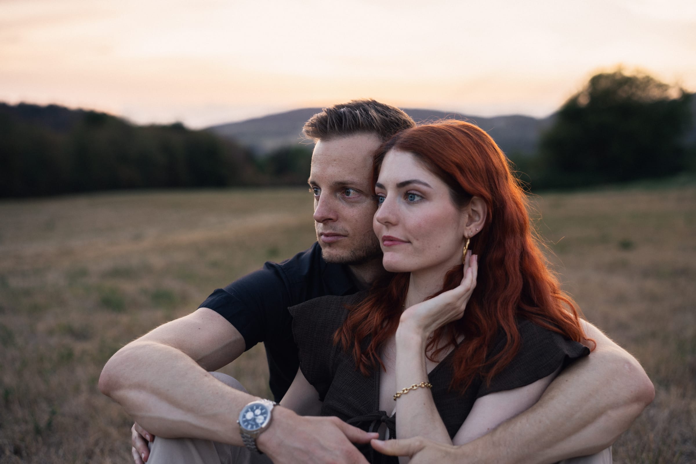 Yanick und Tatjana sitzen im Gras auf der Weide und schauen in die Ferne