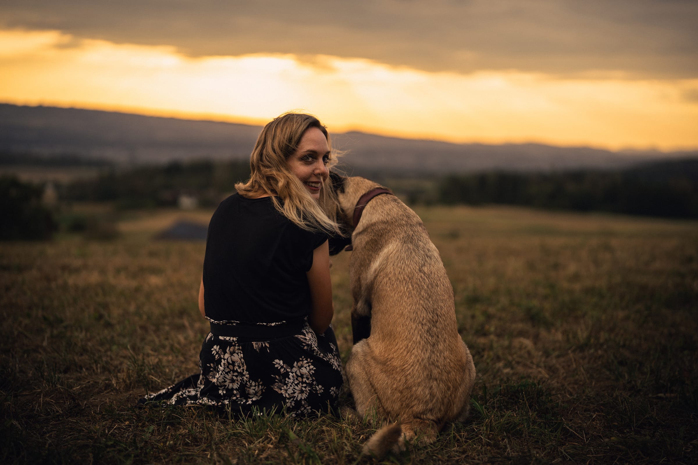 Martina sitzt im Gras, die junge Malinois-Hündin schmiegt sich an sie