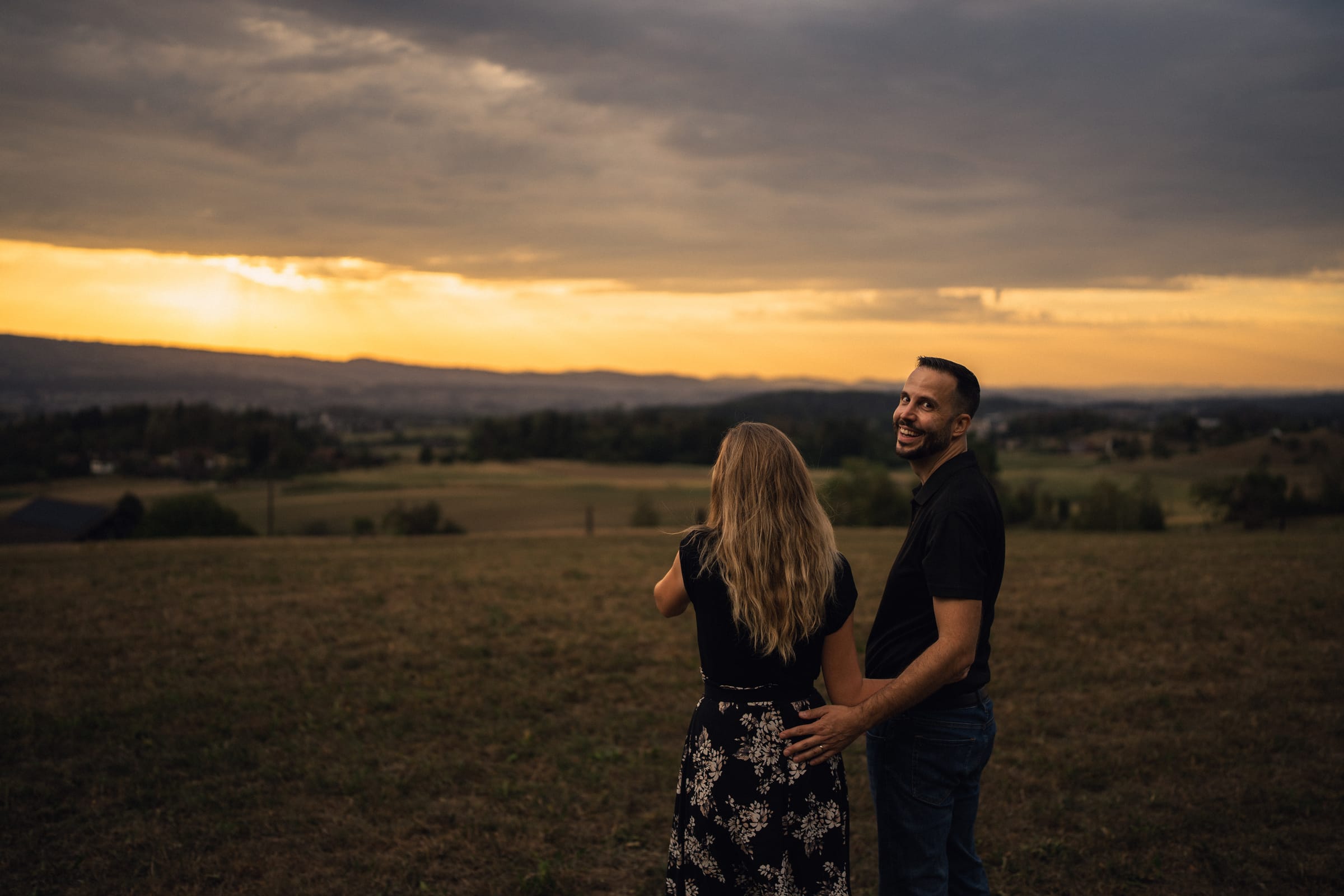 Stephan schaut lachend über die Schulter zurück, Martina neben ihm, Wolkenwand und Abendrot