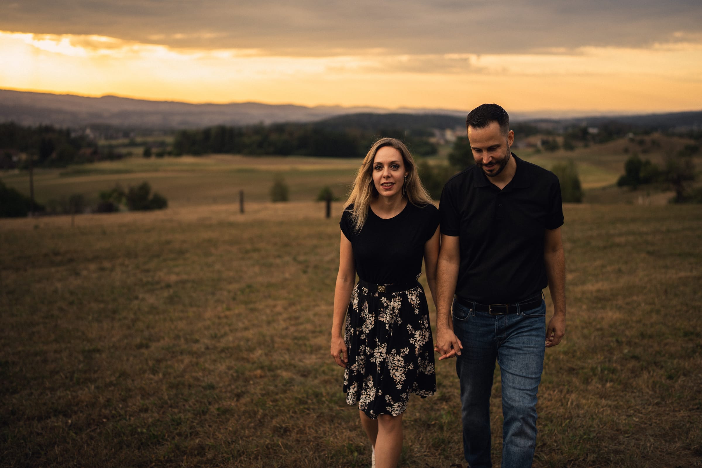 Martina und Stephan gehen Hand in Hand über die Wiese oberhalb von Mettmenstetten